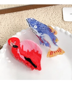 Detail of creative flamingo and blue fish hair claws in an elegant ceramic display