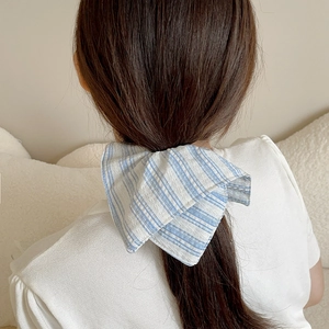 Chouchou rayé bleu et blanc avec nœud papillon porté sur cheveux de femme