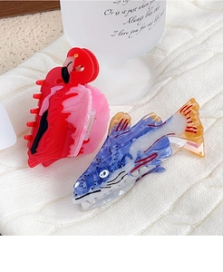 Detail of colorful acetate hair claws in flamingo and trout fish shapes on a cozy knit