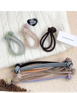 Detail showing seven high-elastic woven hair ties with button knots on a soft knit background