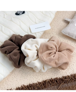 Detailed texture of plush oversized scrunchies in brown, cream, and beige velvet fabric