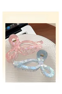 Vue macro des pinces à cheveux en forme de nœud rose et bleu sur un plateau en céramique