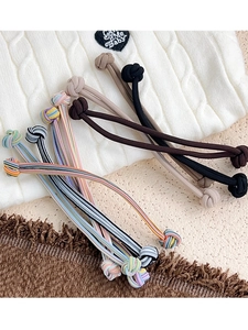 Detailed view of elastic ribbed hair ties in solid and striped colors on knit background