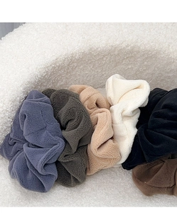 Close-up of fluffy fleece scrunchies in various neutral colors with soft texture