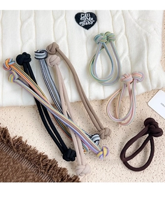 Detail of ribbed elastic hair ties in neutral tones on cozy textured fabric background