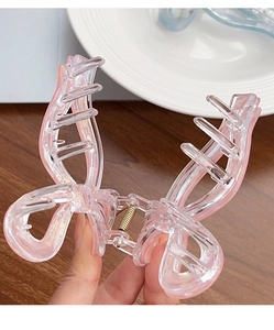 Détail d'une pince à cheveux papillon rose transparent avec ressort doré robuste