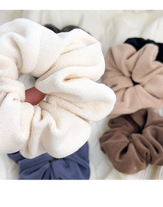 Detailed close-up of soft velvet hair scrunchies in assorted earthy colors and textures