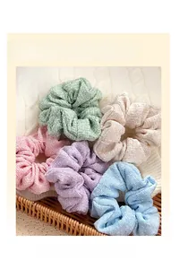 Set of 5 pastel tweed scrunchies in mint, pink, and blue on a soft knit background