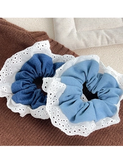 Close-up of blue denim scrunchies with white lace edges on textured fabric background