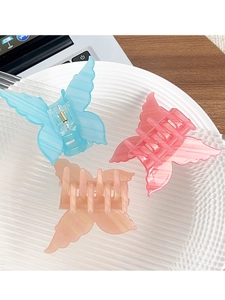 Detailed view of three acrylic butterfly hair clips in blue, pink, and peach colors