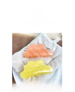 Gros plan sur des pinces à cheveux en forme de nuage rose et jaune, texture nacrée
