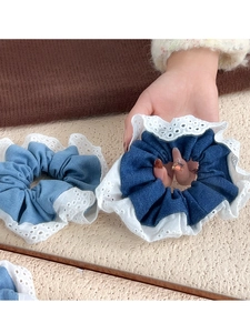 Close-up of contrast lace hair scrunchies in navy and light blue fabric textures