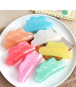 Lot de sept pinces à cheveux en forme de nuage aux motifs marbrés et couleurs pastel sur un plat