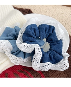 Close-up of blue denim scrunchies set with decorative white eyelet lace edges