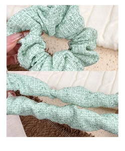 Detail of mint green tweed scrunchie showing woven texture and elastic stretch
