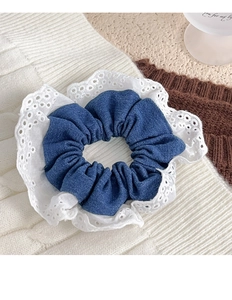 Detailed macro view of the blue denim fabric and white lace trim on the scrunchie