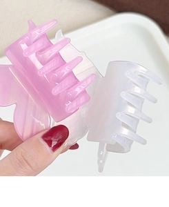 Macro detail of acrylic butterfly hair claw clips in pearlescent purple and white finish