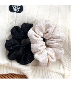 Close-up of black and beige tweed scrunchies showing textured fabric with subtle glitter