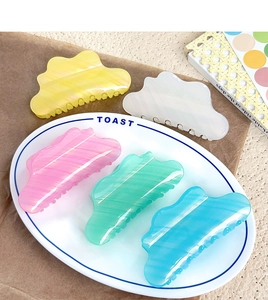 Détail de cinq pinces à cheveux en acétate rayé aux formes de nuages et tons pastel