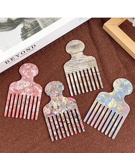 Detailed view of four acetate hair combs with marble patterns on a textured surface