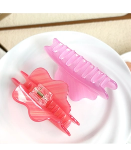 Gros plan de pinces à cheveux roses à rayures présentées sur une assiette blanche