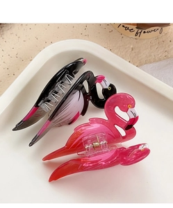 Detailed close-up of flamingo-shaped hair claws in pink and black acrylic material