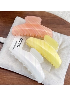 Close-up of French striped acrylic hair claws in pink, yellow and cream marble textures
