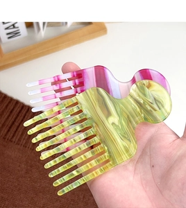 Handheld set of two marble acetate wide tooth hair combs in pink and yellow patterns