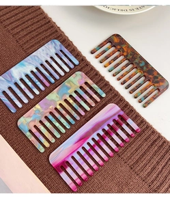 Detailed macro view of four acetate wide-tooth combs with marble and tortoiseshell patterns