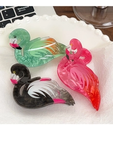Macro shot of three flamingo hair claws with marble texture in pink, green, and black