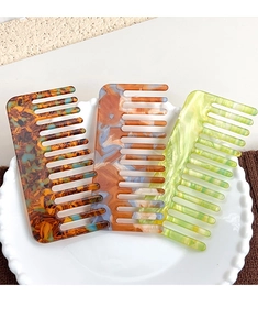 Detailed macro view of acetate wide-tooth combs with elegant marble and amber patterns