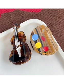 Artistic cello and palette shaped acetate hair clips with glossy finish on a tray