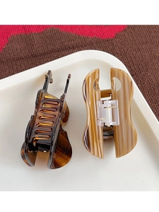 Detail of cello-shaped acetate hair claw clips with tortoiseshell and wood patterns