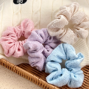 Chic tweed scrunchie set in pink, purple, beige, and blue on woven tray background