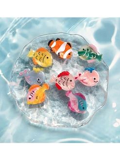 Close-up of colorful ocean fish acetate hair clips on ice texture background