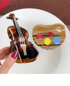 Detailed close-up of violin and palette shaped acetate hair claws for women