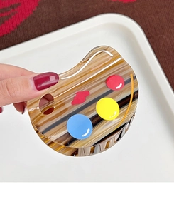 Detailed view of handmade acetate palette hair claw with amber shell and artistic color dots