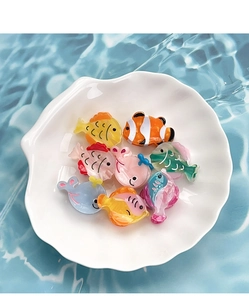 Detail of cute ocean creature hair clips featuring colorful acetate fish on shell tray