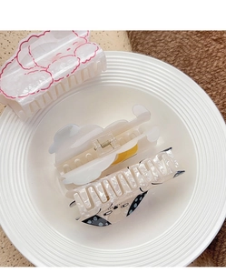 Detail of large acrylic hair claw clips featuring cartoon dog and pink cloud designs