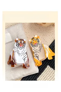 Detail showing two cartoon tiger hair claw clips in yellow and white on a canvas bag
