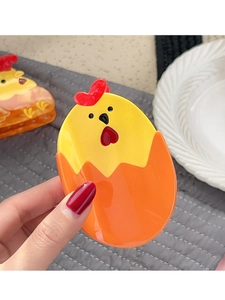 Détail d'une pince à cheveux poussin de dessin animé avec peigne rouge en forme de cœur
