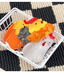 Détail de pinces à cheveux poulet colorées dans un panier blanc sur fond à carreaux