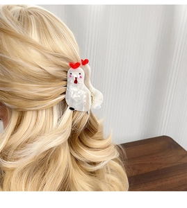 Pince à cheveux coq en acétate avec détail cœur rouge sur de longs cheveux blonds