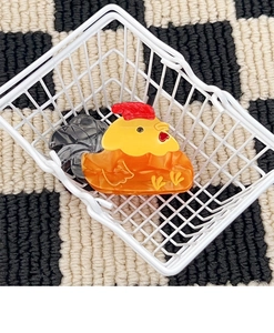 Détail de pince à cheveux coq en acétate marbré placée dans un mini panier