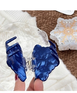Dettaglio del fermaglio per capelli marmorizzato blu scuro con strass a forma di fiocco