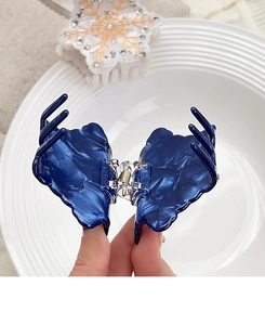 Dettaglio di elegante molletta per capelli in acetato marmorizzato con fiocco di neve e strass