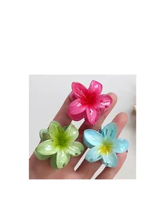 Détails de trois pinces à cheveux en forme de fleur de frangipanier colorées en main