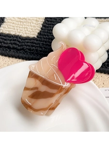Macro detail of acetate ice cream claw clip with pink heart on marble texture base