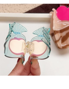 Detail of translucent candy-shaped hair claw clip with pink apple motif and metal spring