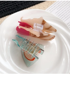 Detail of acetate shark hair clips in marble cream and translucent blue on a white plate